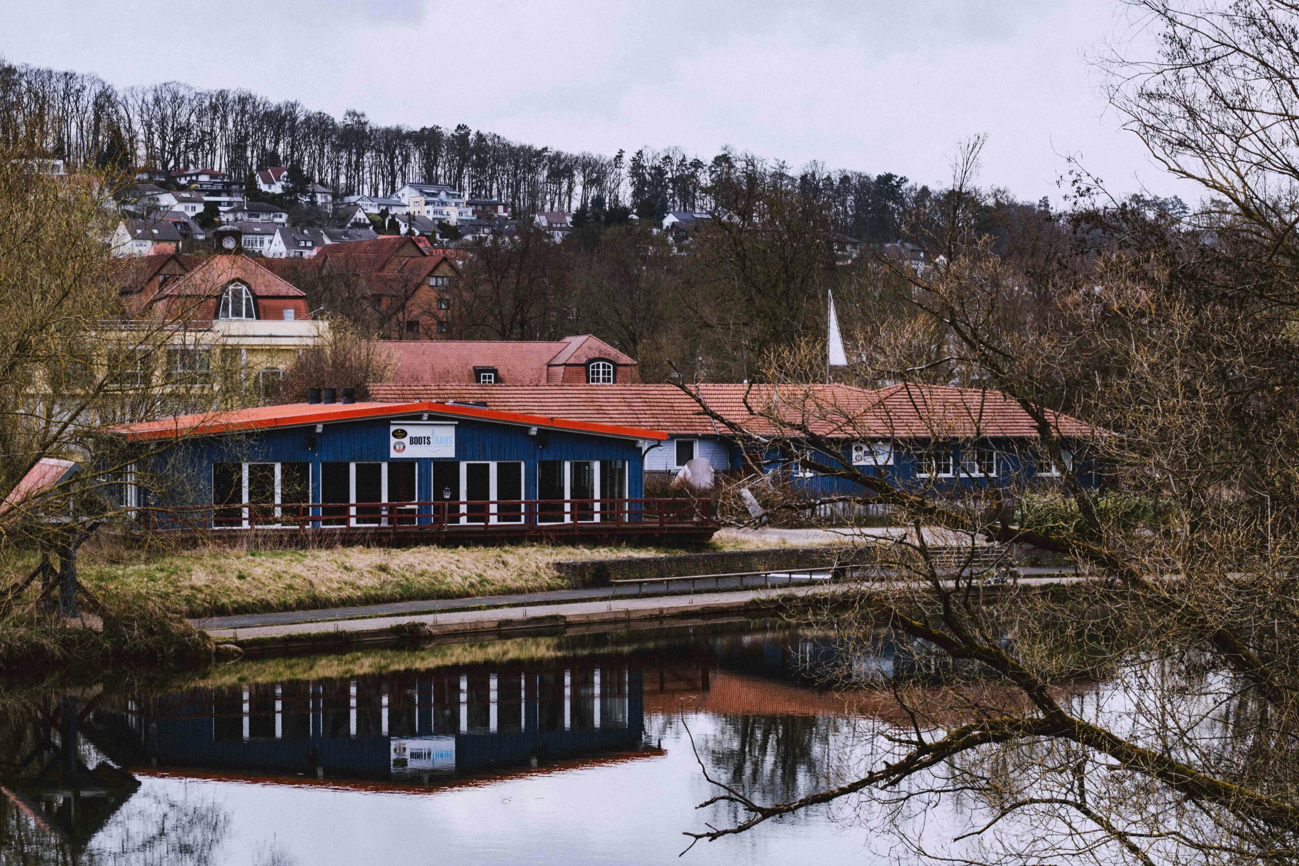 Charmantes Bergdorf, das sich unter einem bewölkten Himmel in einem ruhigen Fluss spiegelt, ideales Reiseziel.
