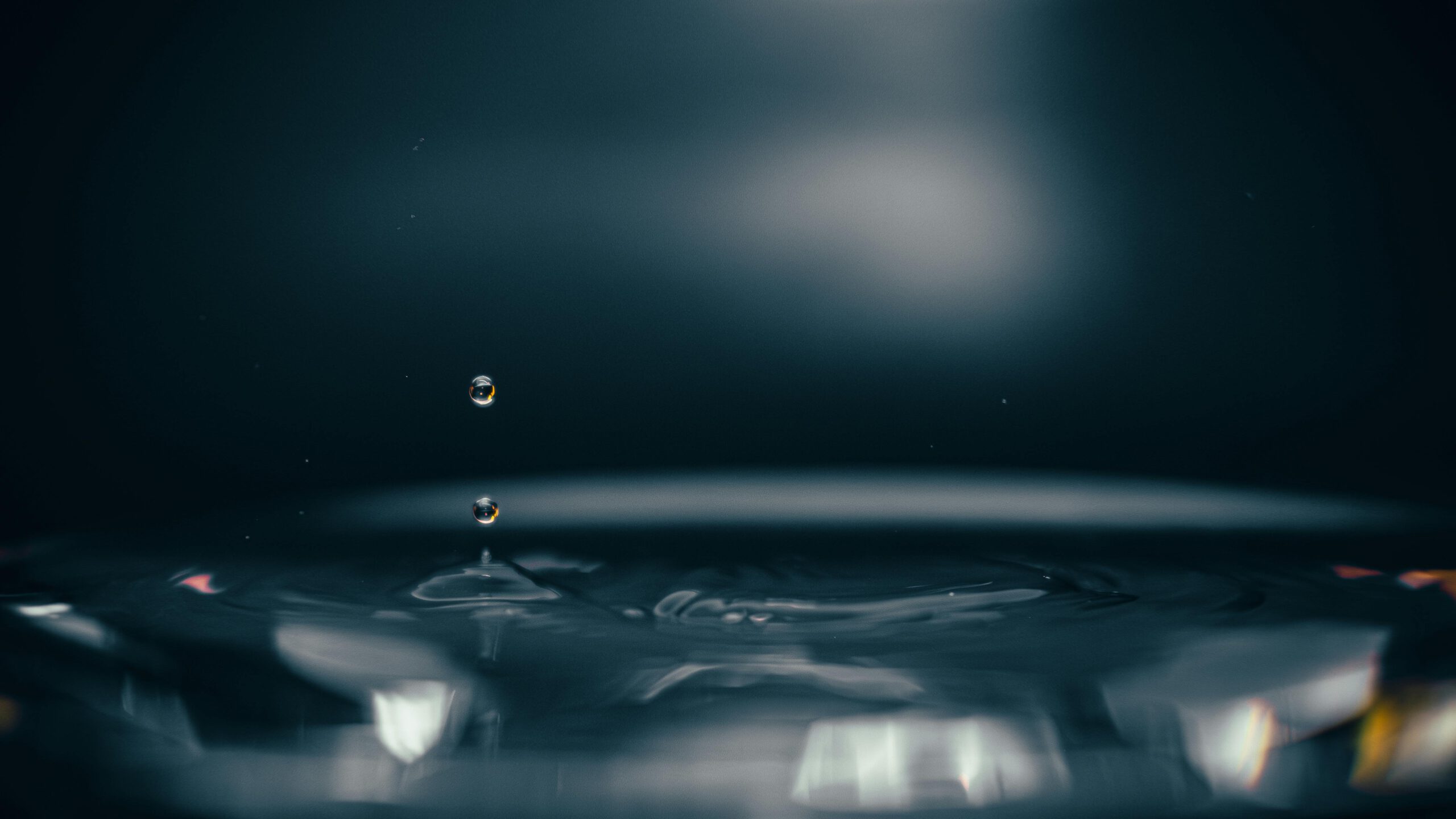 Nahaufnahme eines Wassertropfens, der mit Spiegelungen und Weichzeichner einen ruhigen und künstlerischen Effekt erzeugt.