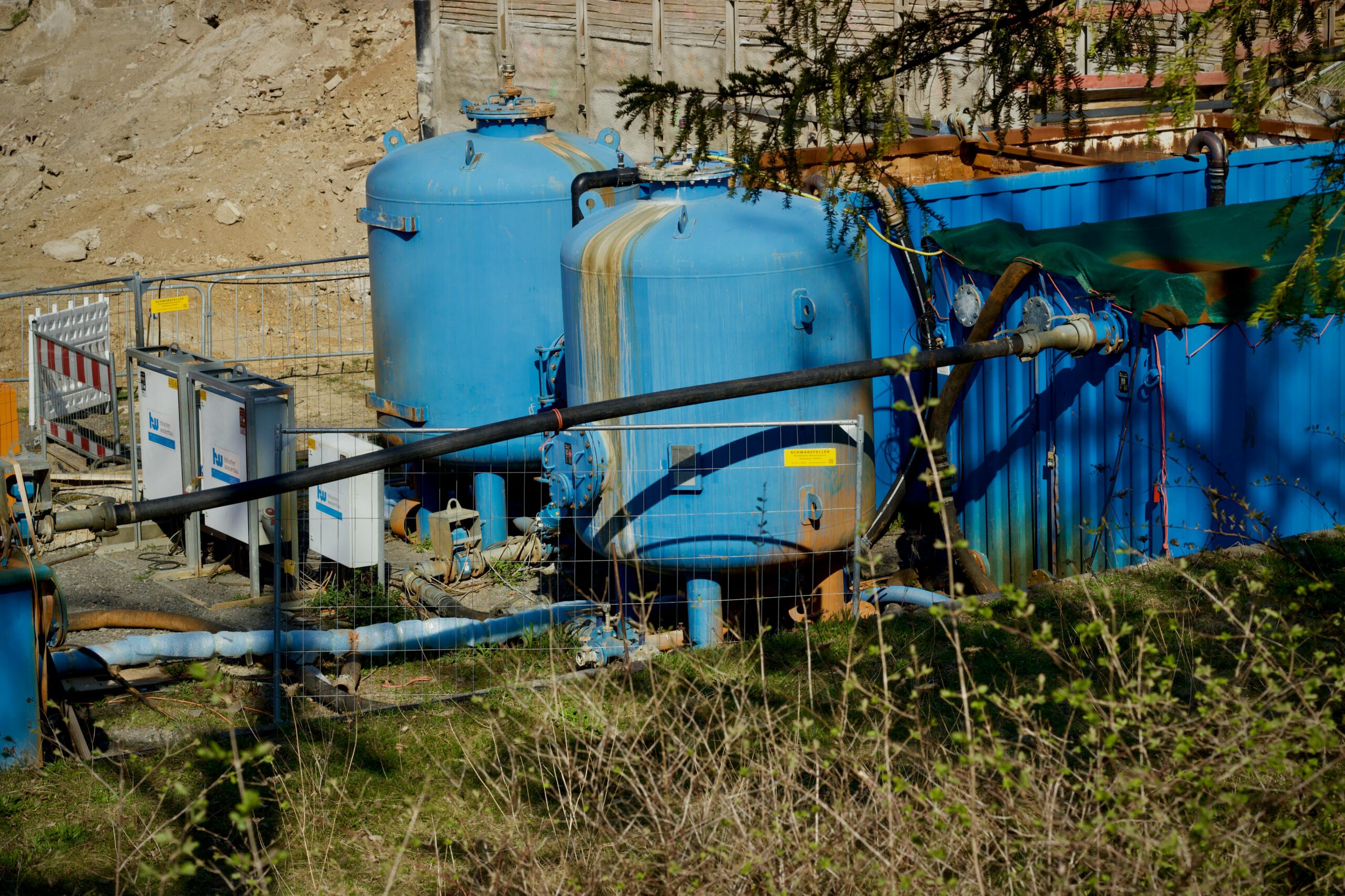 Industrielle Wasserfiltrationsanlage im Freien mit großen blauen Tanks im Sonnenlicht.